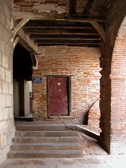 Perspective sur une poterne de couleur bordeaux, sous les arcades de la place Saint-Salvy