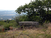 Petit dolmen aux dimensions régulières dont la pierre sommitale est partaitement plane. Quelques arbres, et vue sur les lointains
